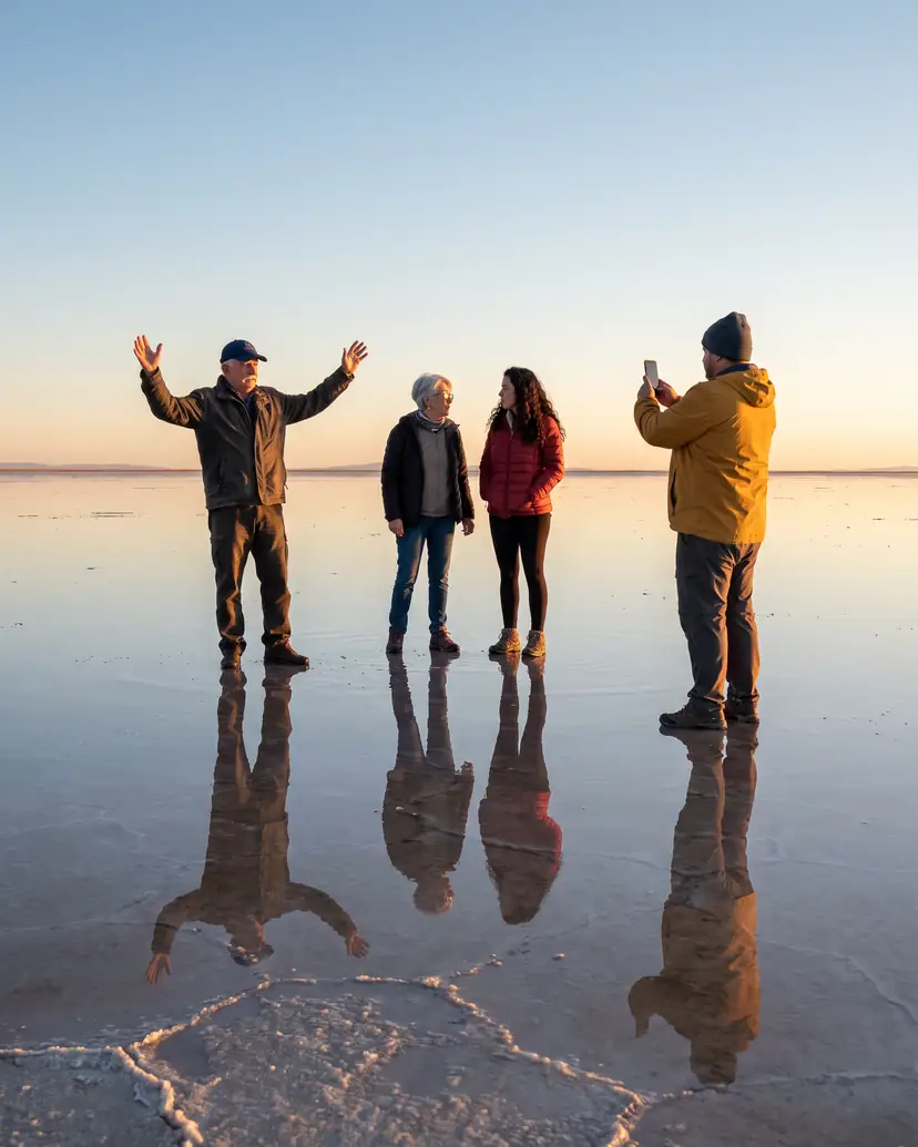 Personas sobre el espejo de agua del Salar de Uyuni al amanecer